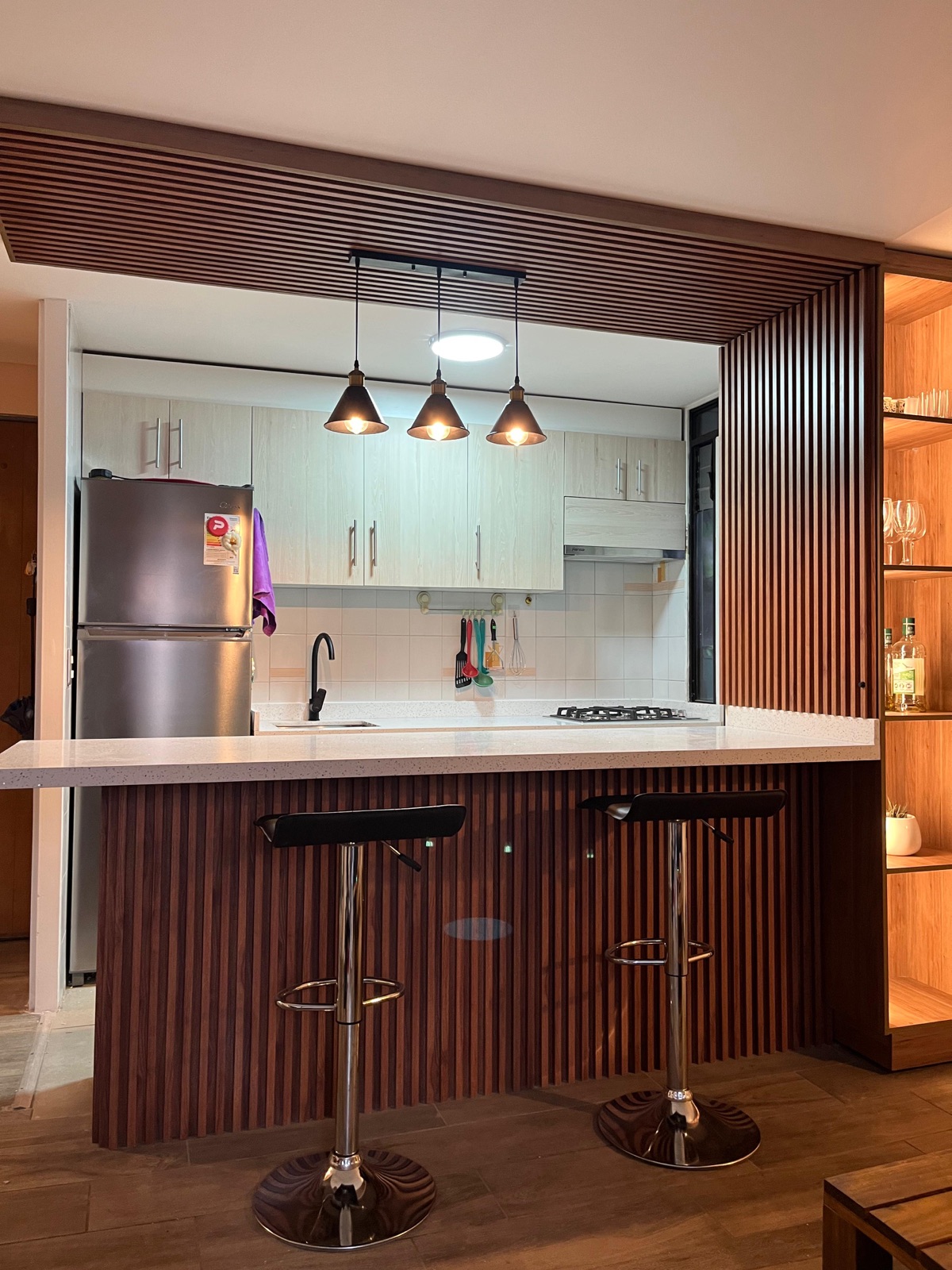 Barra de cocina revestida en listones de madera con repisa iluminada y piso flotante
