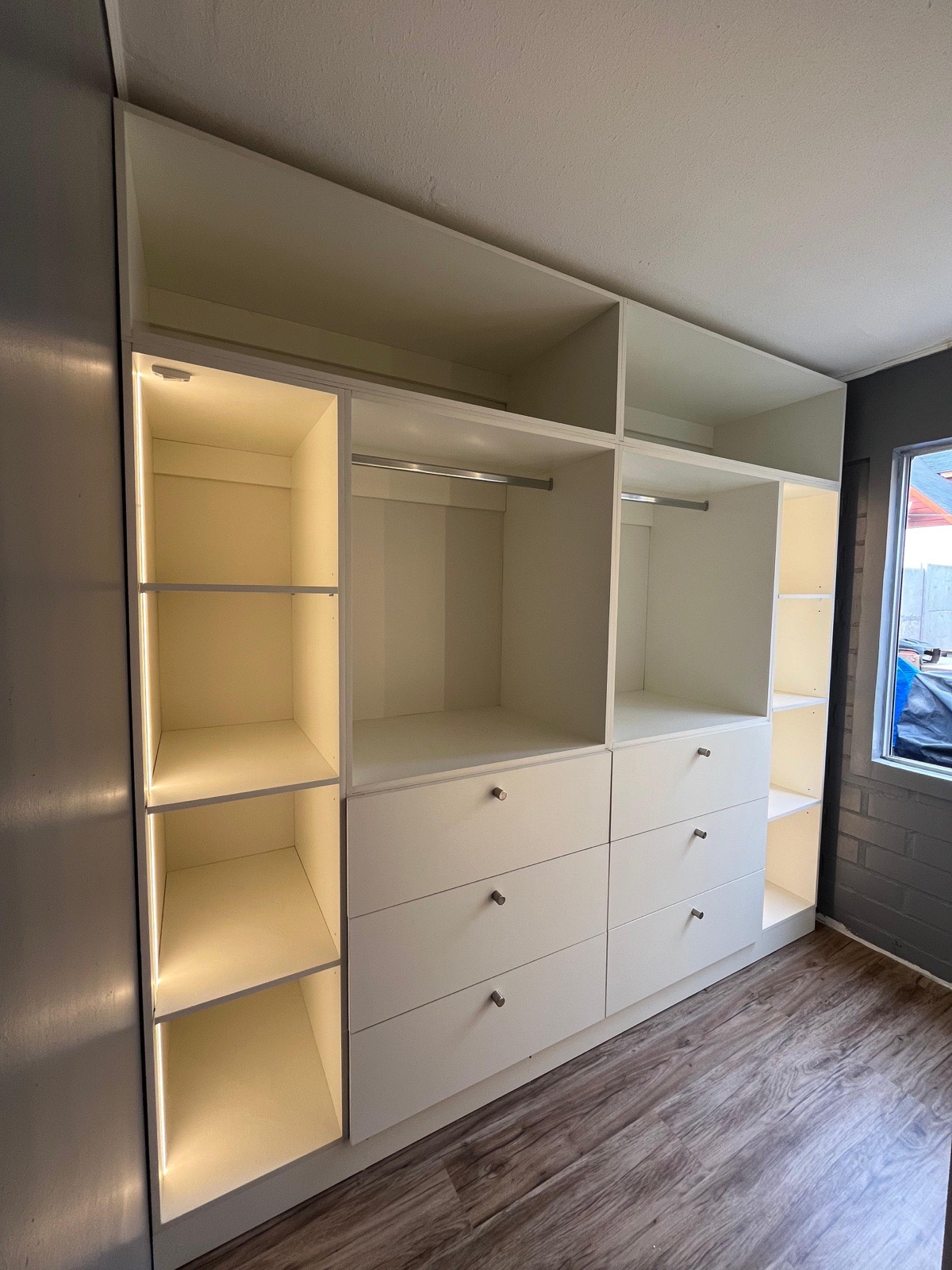 Walk-in closet abierto con maletero, colgador, cajoneras y repiseros con iluminación Led.