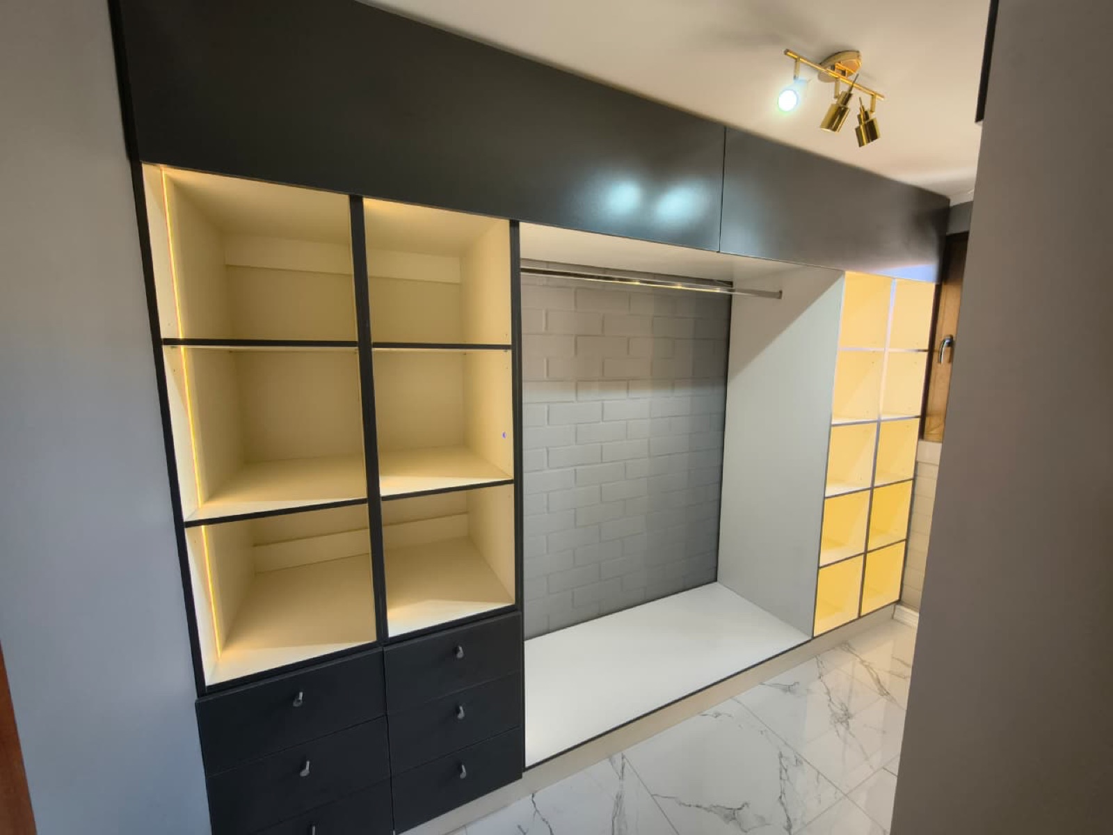 Walk-in closet con puertas en maletero, colgador y repisas con luz Led.