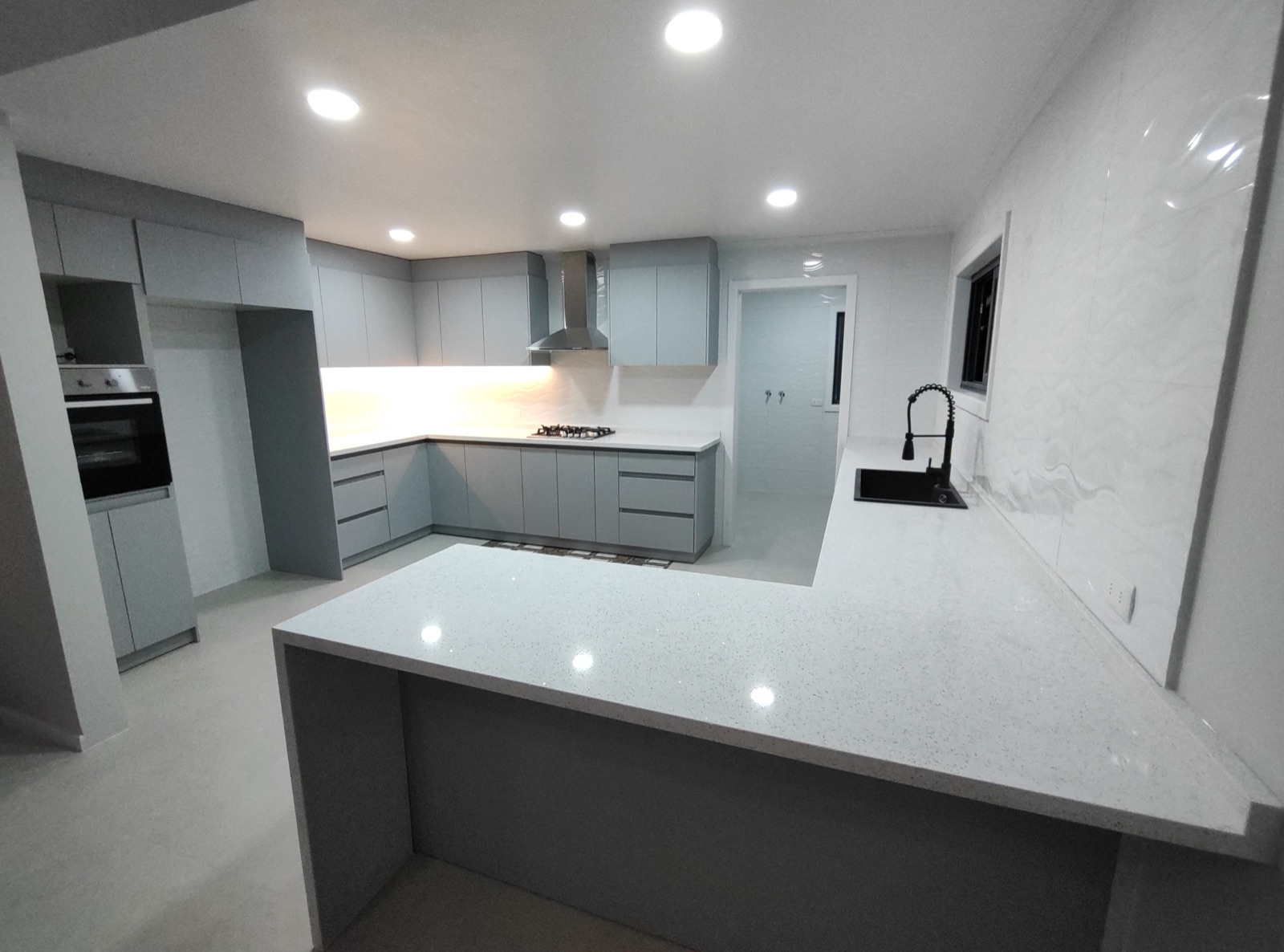 Cocina blanca y gris con península, campana inox y cubierta de cuarzo