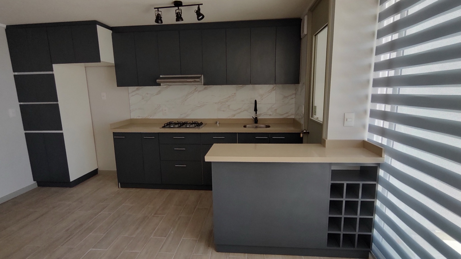 Cocina gris con península, botellero integrado, cubierta de madera y focos dirigibles