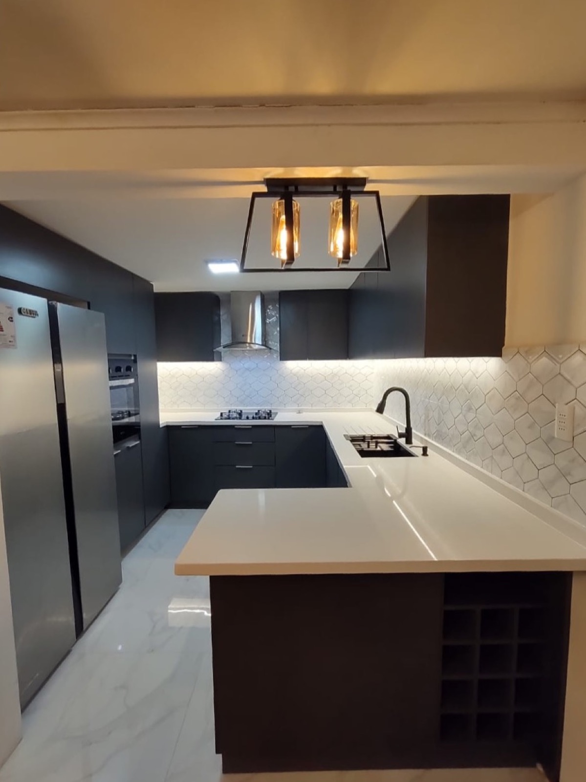 Cocina oscura con isla, botellero integrado y lámpara colgante de fierro negro
