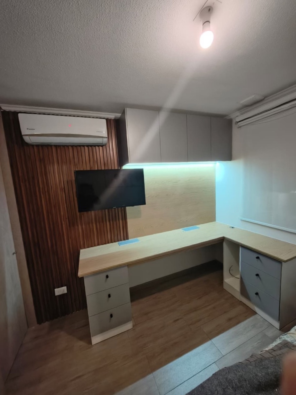 Escritorio en L. Muebles aéreos con luz Led, cubierta con enchufes plegables y decorativo wall panel en muro.