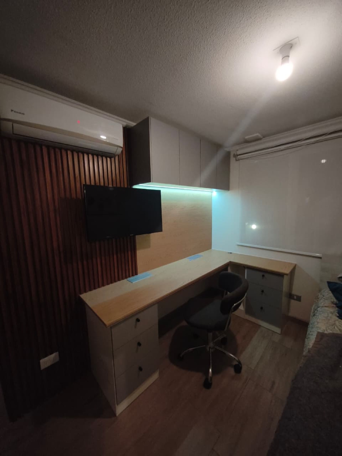 Escritorio en L. Muebles aéreos con luz Led y cubierta con enchufes plegables.