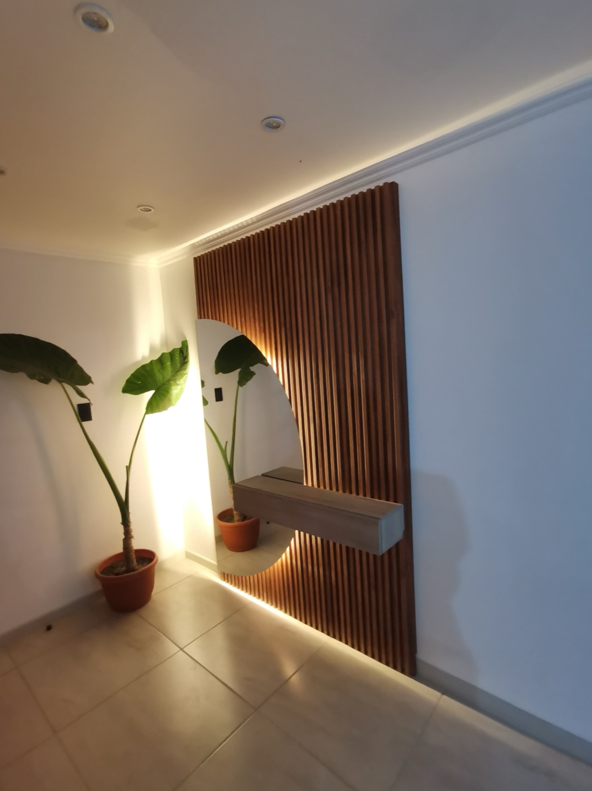 Hall entrada con wall panel decorativo y espejo media luna.
