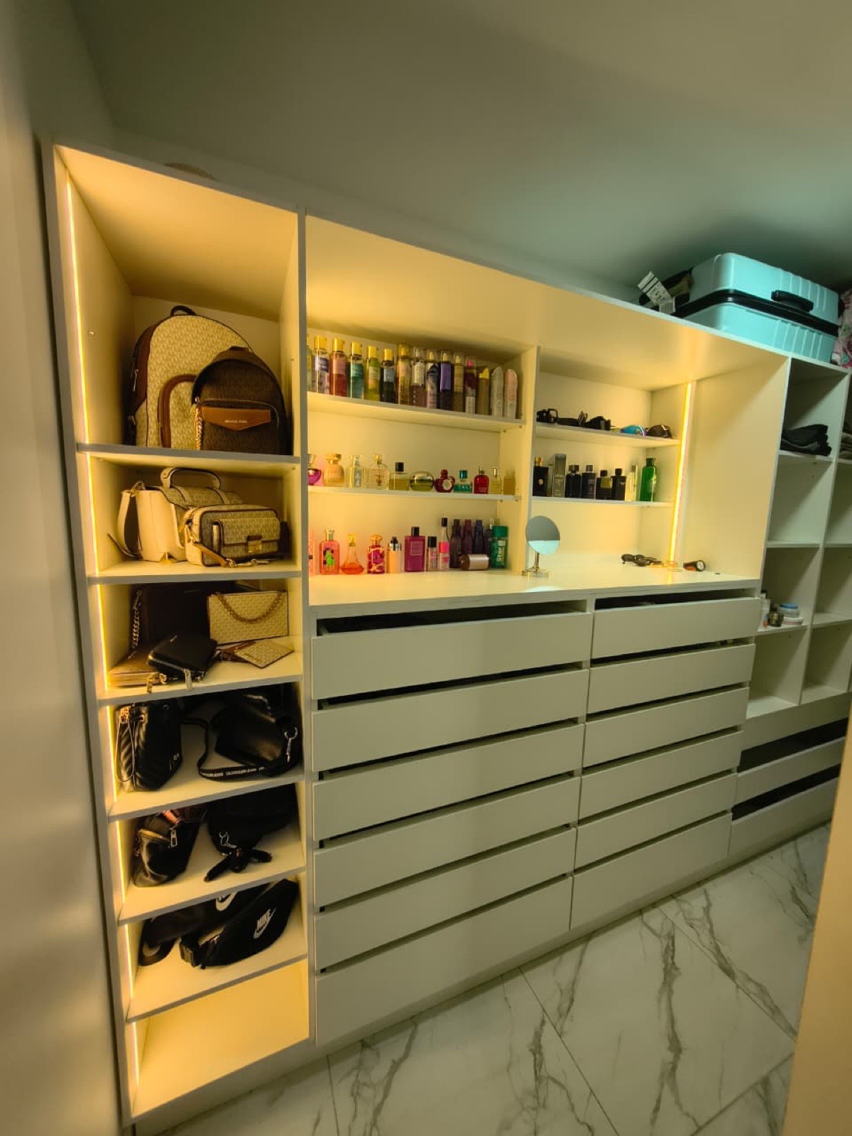 Walk-in closet con repisas, iluminación Led, cajoneras y cubículos de almacenamiento.